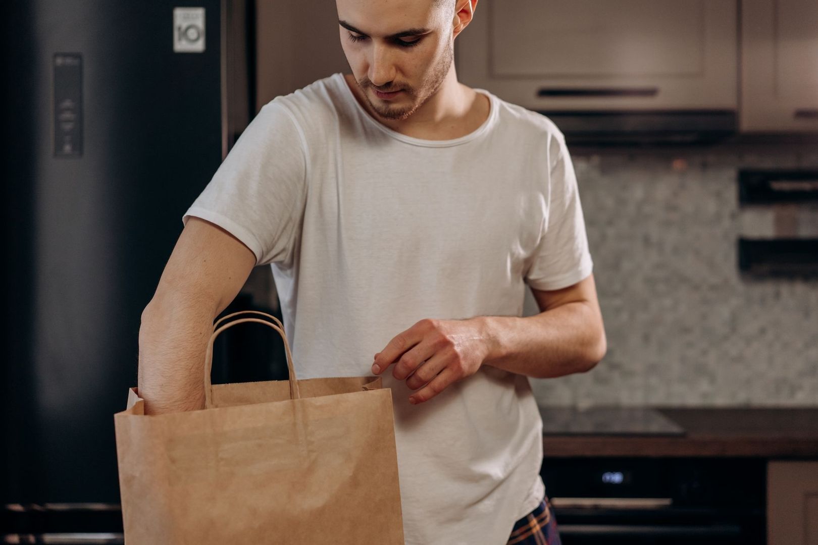 Man packar upp en brun papperspåse i köket