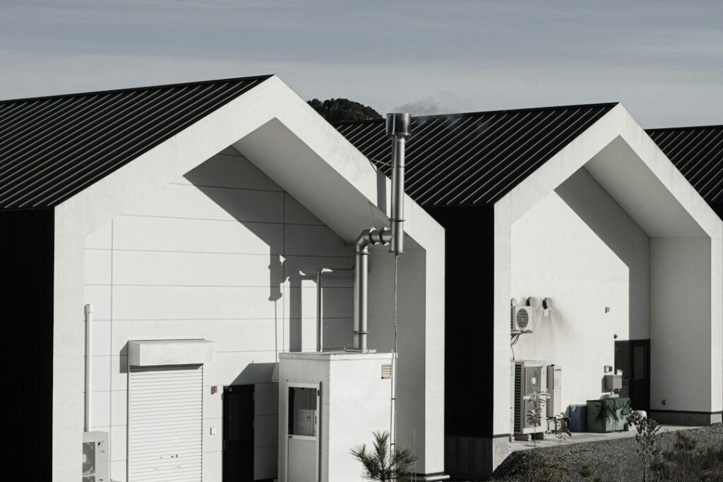 Modern vit byggnad med skorsten och synliga värme- och ventilationsaggregat