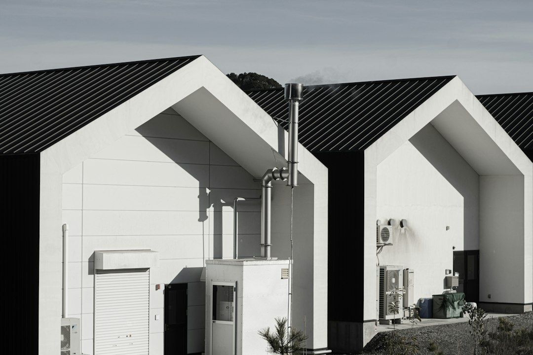 Modern vit byggnad med skorsten och synliga värme- och ventilationsaggregat