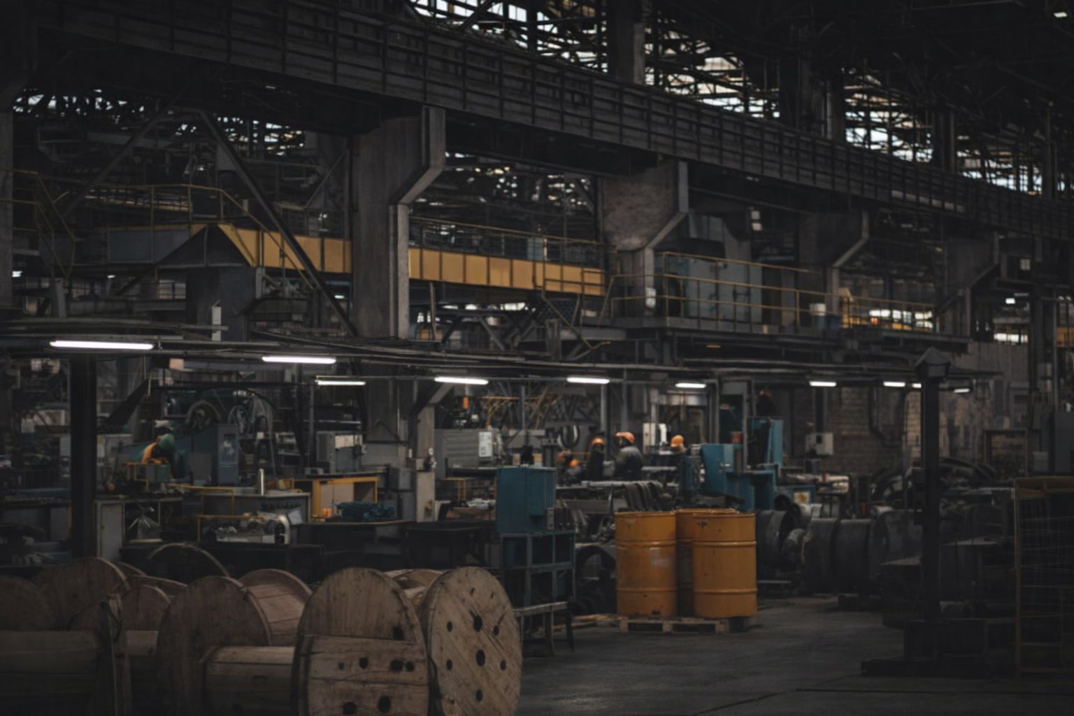 Interiör av en stor industrihall med maskiner och kabeltrummor.
